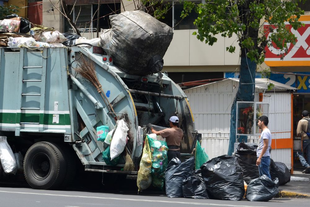 A garbage truck in San Francisco with a man loading trash into it during a clean-out service.